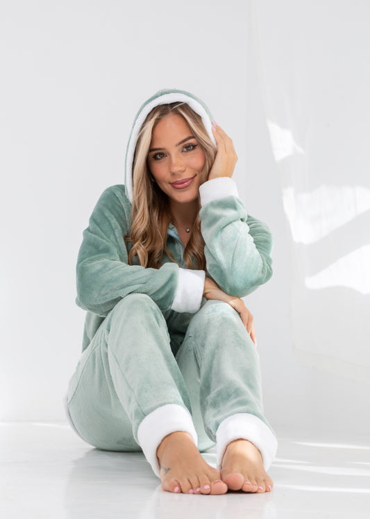 Woman wearing a green onesie with white cuffs and hem on a white background